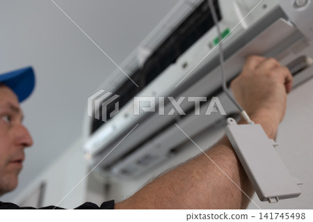 Technician checking air conditioner unit. Repairman installing cooling system equipment at home. Technician checking air conditioner unit. Repairman installing cooling system equipment at home. 141745498