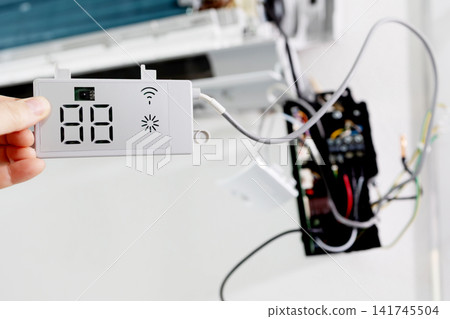 Technician holding display module for split system air conditioner. Repair and maintenance concept. 141745504