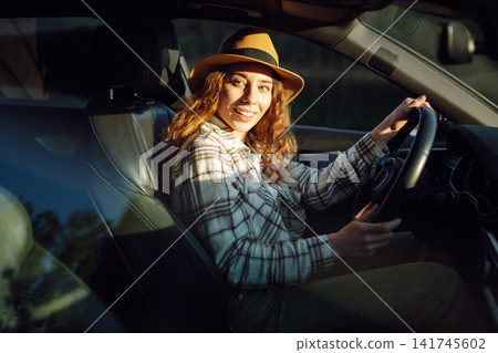 Female driver. Portrait of young woman is driving a car. Automobile travel. Car sharing. Female driver. Portrait of young woman is driving a car. Automobile travel. Car sharing. 141745602