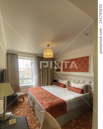 Cozy hotel bedroom interior with double bed, warm lighting and elegant classic design Cozy hotel bedroom interior with double bed, warm lighting and elegant classic design 141745650