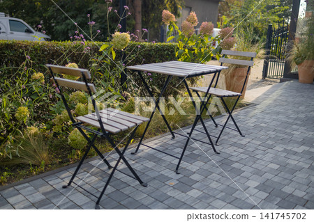 Empty folding metal tables and chairs on paved terrace outdoors 141745702