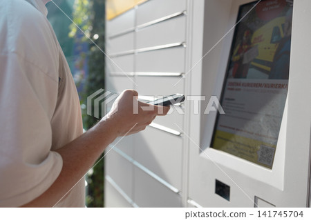 Young man with backpack using outdoor automated parcel locker station 141745704