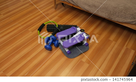 Compact home equipment set on a wooden floor. Stepper, dumbbells, foam roller, and Pilates ring. Small apartment workout. Home Gym Setup. Space-Saving Fitness. Weight Loss Programs. Self-Care Routine Compact home equipment set on a wooden floor. Stepper, dumbbells, foam roller, and Pilates ring. Small apartment workout. Home Gym Setup. Space-Saving Fitness. Weight Loss Programs. Self-Care Routine 141745964