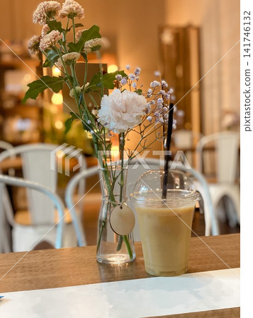Cozy cafe scene with a glass of iced coffee and a small bouquet of flowers Cozy cafe scene with a glass of iced coffee and a small bouquet of flowers 141746132
