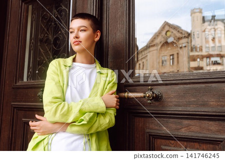 Stylish young woman with short haircut posing on city streets. The concept of fashion, style. Stylish young woman with short haircut posing on city streets. The concept of fashion, style. 141746245