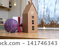 Minimalist craft paper advent calendar box shaped like house stands on kitchen wooden table. Festive handmade DIY cardboard surprise packaging with numbers for winter holiday family tradition. 141746343