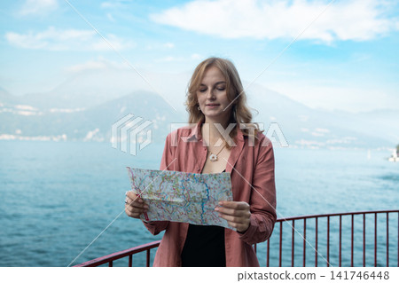 Young woman tourist holding a paper map at Lake Como Young woman tourist holding a paper map at Lake Como 141746448