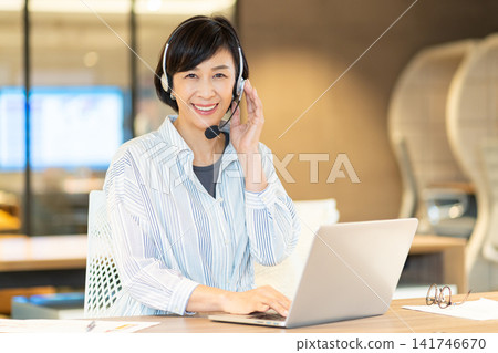 一位微笑的資深女操作員正在使用電腦。 一位微笑的資深女操作員正在使用電腦。 141746670