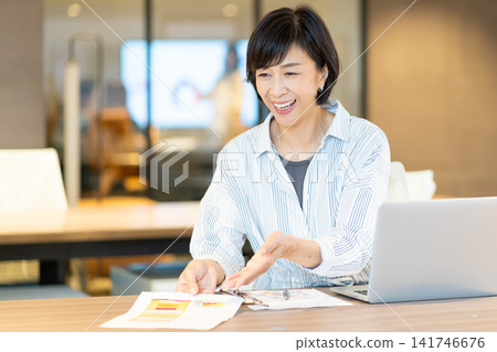 A middle-aged woman using a computer at ShareOffice. A middle-aged woman using a computer at ShareOffice. 141746676