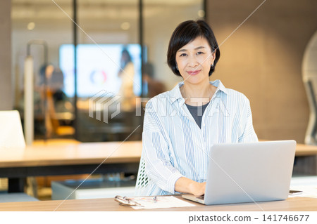 A middle-aged woman using a computer at ShareOffice. A middle-aged woman using a computer at ShareOffice. 141746677