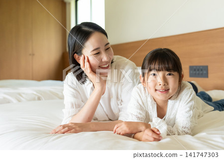 A parent and child lying on a bed A parent and child lying on a bed 141747303