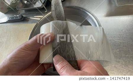 廚師用手將白蘿蔔削成桂切薄片。 廚師用手將白蘿蔔削成桂切薄片。 141747419