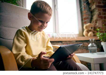 Focused five-year-old boy watching content on tablet during quiet leisure time at home Focused five-year-old boy watching content on tablet during quiet leisure time at home 141747773