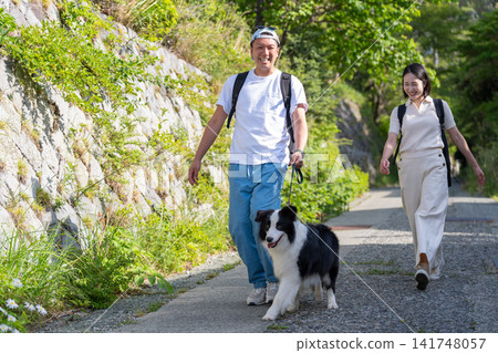 一對年輕夫婦帶著他們的寵物——一隻邊境牧羊犬——旅行。 一對年輕夫婦帶著他們的寵物——一隻邊境牧羊犬——旅行。 141748057