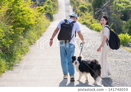 A couple enjoying a trip with their dog, seen from behind. A couple enjoying a trip with their dog, seen from behind. 141748059