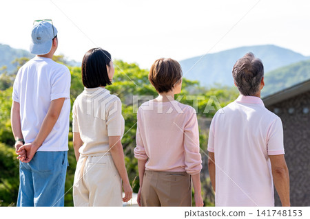 一家兩代人從度假屋眺望風景的背影。 一家兩代人從度假屋眺望風景的背影。 141748153