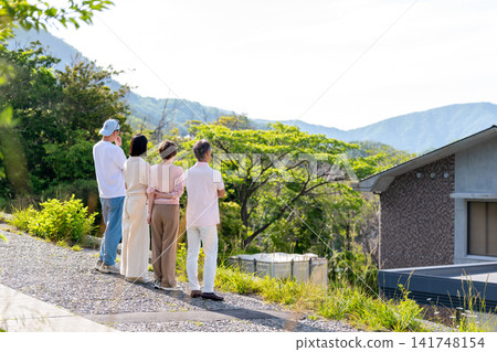 一家兩代人從度假屋眺望風景的背影。 一家兩代人從度假屋眺望風景的背影。 141748154