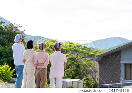 一家兩代人從度假屋眺望風景的背影。 一家兩代人從度假屋眺望風景的背影。 141748156