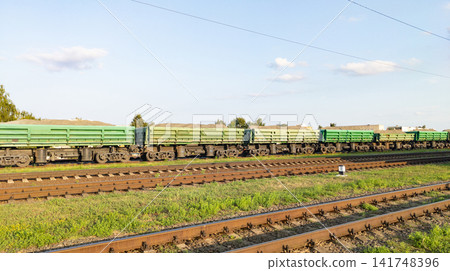Railway wagons. Green hopper dump cars for bulk cargo standing on multiple railroad tracks. Concept of heavy industrial logistics, raw material transport Railway wagons. Green hopper dump cars for bulk cargo standing on multiple railroad tracks. Concept of heavy industrial logistics, raw material transport 141748396