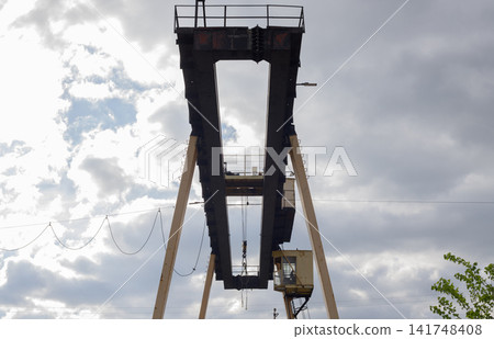 Low Angle View of Industrial Gantry Crane Steel Structure Against Cloudy Sky Low Angle View of Industrial Gantry Crane Steel Structure Against Cloudy Sky 141748408