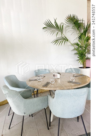 Modern cafe interior with round table, chairs, plant, soft daylight, minimal design Modern cafe interior with round table, chairs, plant, soft daylight, minimal design 141748557