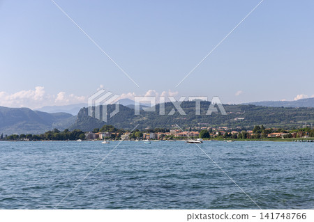 Opposite shore of Lake Garda with green hills, lakeside towns and small boats Opposite shore of Lake Garda with green hills, lakeside towns and small boats 141748766