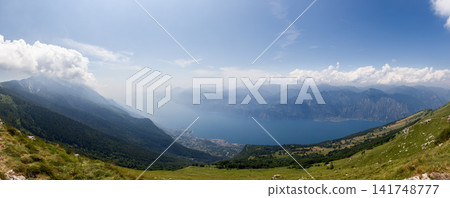 Green mountain valley opening toward a wide Lake Garda panorama from Monte Baldo Green mountain valley opening toward a wide Lake Garda panorama from Monte Baldo 141748777