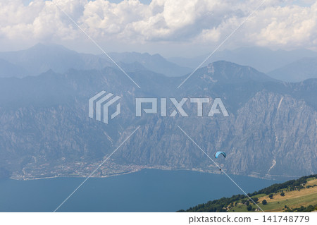Paraglider above Lake Garda with steep mountains viewed from Monte Baldo Paraglider above Lake Garda with steep mountains viewed from Monte Baldo 141748779