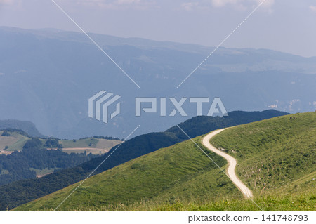 Mountain track winding across a green hillside on Monte Baldo in Italy Mountain track winding across a green hillside on Monte Baldo in Italy 141748793