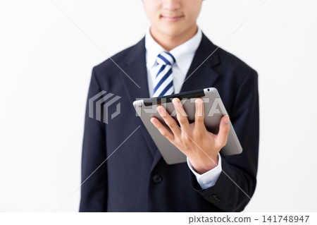 一位身穿西裝的年輕商人,手裡拿著平板電腦。 一位身穿西裝的年輕商人,手裡拿著平板電腦。 141748947