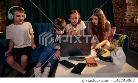 Group of school-age children gathering around laptop and mobile devices Group of school-age children gathering around laptop and mobile devices 141749008