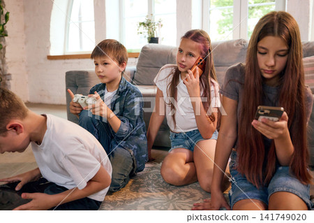 Group of school-age friends browsing smartphones together on sofa at home Group of school-age friends browsing smartphones together on sofa at home 141749020