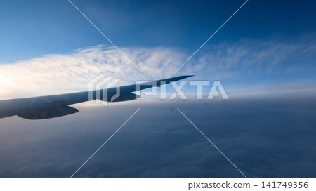 aerial view of airplane wing view soaring above a vast sea of soft white clouds under a clear blue sky with a textured landscape and copy space aerial view of airplane wing view soaring above a vast sea of soft white clouds under a clear blue sky with a textured landscape and copy space 141749356