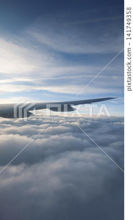 aerial view of airplane wing view soaring above a vast sea of soft white clouds under a clear blue sky with a textured landscape and copy space aerial view of airplane wing view soaring above a vast sea of soft white clouds under a clear blue sky with a textured landscape and copy space 141749358