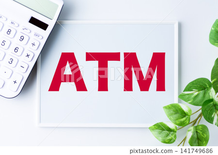 一塊寫著「ATM」字樣的白板和一台白色計算器 一塊寫著「ATM」字樣的白板和一台白色計算器 141749686