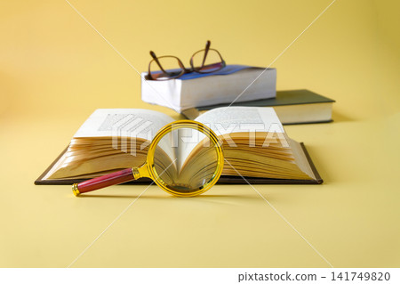A magnifying glass with opened books. Concept of education and research. A magnifying glass with opened books. Concept of education and research. 141749820