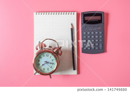Vintage alarm clock lay on notebook on color background. Vintage alarm clock lay on notebook on color background. 141749880