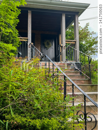 Cozy Wooden Porch Entrance to a Village House Surrounded by Lush Greenery Cozy Wooden Porch Entrance to a Village House Surrounded by Lush Greenery 141750083