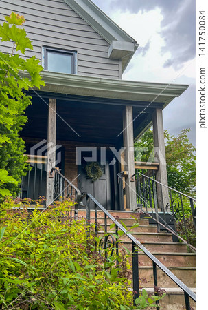 Cozy Wooden Porch Entrance to a Village House Surrounded by Lush Greenery Cozy Wooden Porch Entrance to a Village House Surrounded by Lush Greenery 141750084