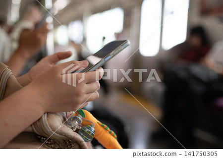 A woman's hands operating her smartphone on a train. A woman's hands operating her smartphone on a train. 141750305