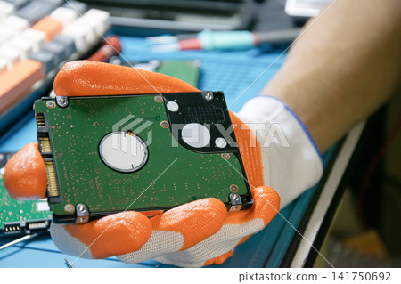 A technician about to repair a hard drive, a computer component. A technician about to repair a hard drive, a computer component. 141750692