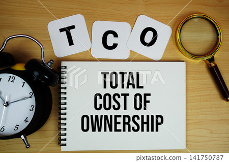 TCO Total Cost of Ownership text written on notepad with magnifying glass and alarm clock on wooden background TCO Total Cost of Ownership text written on notepad with magnifying glass and alarm clock on wooden background 141750787