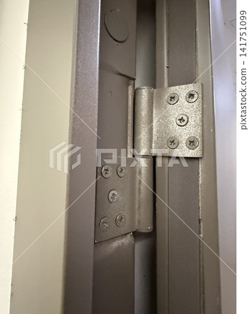 Metal hinge on industrial door with screws and metallic texture, close-up detail and background Metal hinge on industrial door with screws and metallic texture, close-up detail and background 141751099
