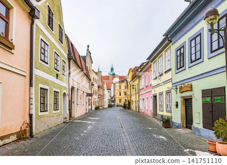 A cobblestone alley lined with pastel-colored historical buildings in the old town of České Budějovice. A cobblestone alley lined with pastel-colored historical buildings in the old town of České Budějovice. 141751110