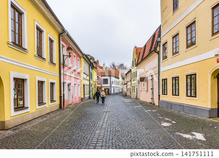 A cobblestone alley lined with pastel-colored historical buildings in the old town of České Budějovice. A cobblestone alley lined with pastel-colored historical buildings in the old town of České Budějovice. 141751111