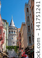 Istanbul, turkey, august 2, 2025 galata tower standing tall between colorful buildings in a narrow street of istanbul, turkey, a popular travel destination 141751241