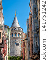 Istanbul, turkey, august 2, 2025 galata tower standing tall, seen through a narrow street flanked by colorful traditional beyoglu buildings under a clear sky 141751242