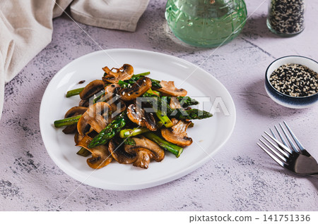 Delicious roasted asparagus and mushrooms on a white plate on the table Delicious roasted asparagus and mushrooms on a white plate on the table 141751336
