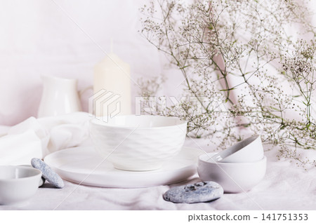 White ceramic dishes, white linen cloth, fabrics and dried flowers on the table White ceramic dishes, white linen cloth, fabrics and dried flowers on the table 141751353