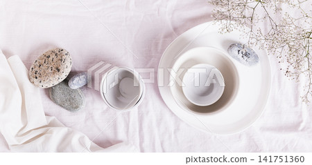 Coarse linen drapery for a kitchen table with ceramic dishes in white tones top view web banner Coarse linen drapery for a kitchen table with ceramic dishes in white tones top view web banner 141751360